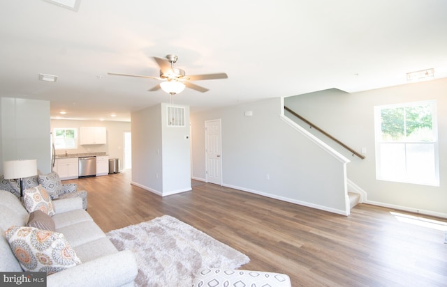 living room featuring light wood-type flooring, ceiling fan, and sink