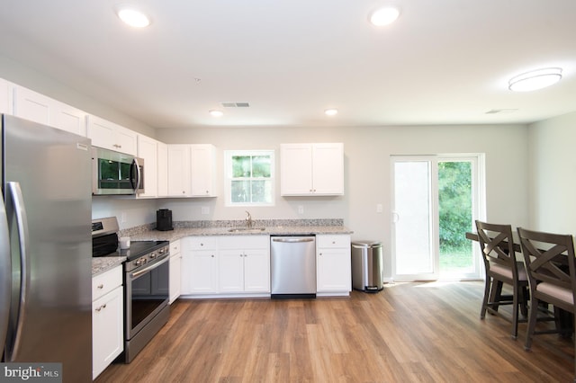 kitchen with stainless steel appliances, white cabinets, hardwood / wood-style floors, and sink