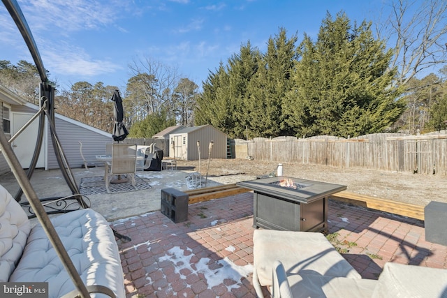 view of patio with an outdoor fire pit and a shed