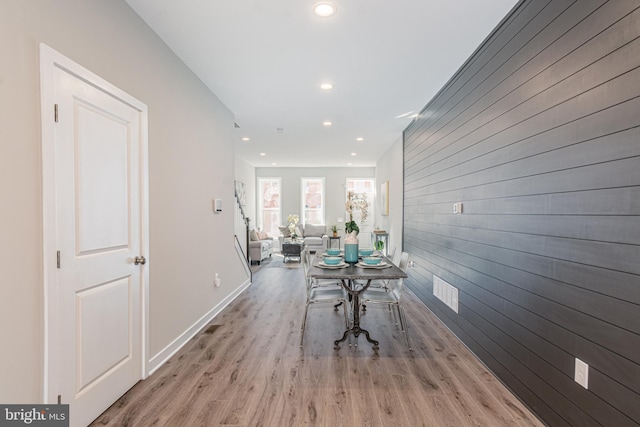 hall with light wood-type flooring and wooden walls