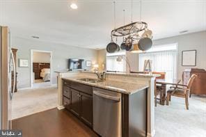 kitchen featuring appliances with stainless steel finishes, light colored carpet, light stone counters, dark brown cabinetry, and sink