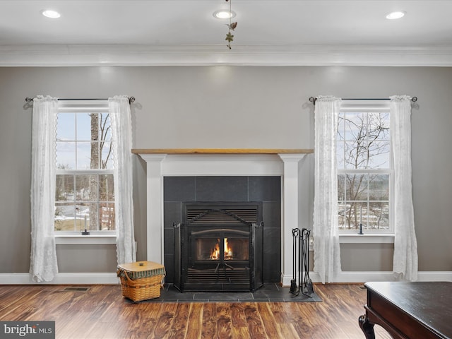 interior details with hardwood / wood-style floors, crown molding, and a tiled fireplace