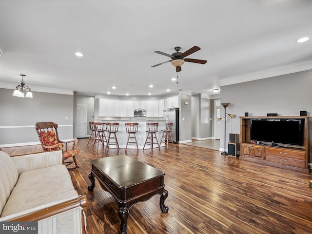 living room with dark hardwood / wood-style flooring, ceiling fan with notable chandelier, and crown molding