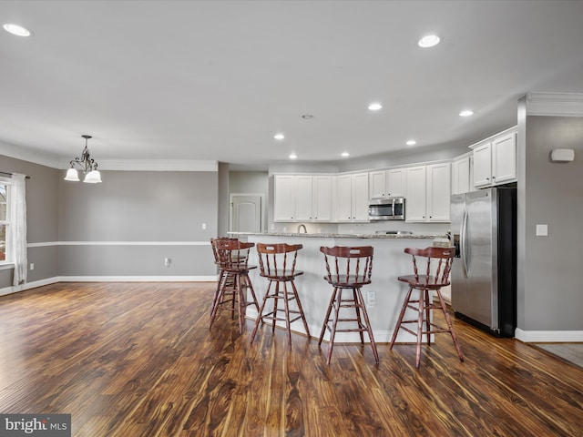 kitchen featuring pendant lighting, white cabinetry, a kitchen breakfast bar, stainless steel appliances, and light stone counters