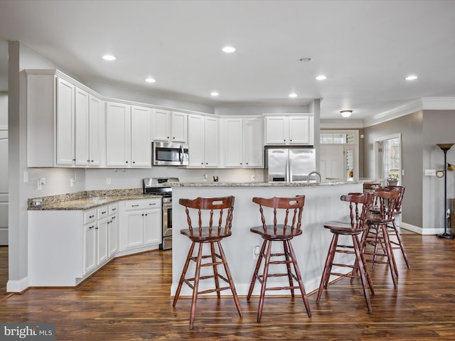 kitchen featuring a kitchen island with sink, light stone counters, stainless steel appliances, and white cabinetry