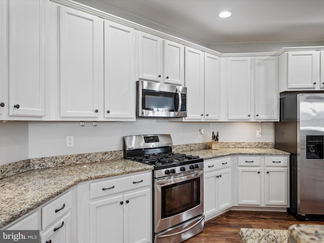 kitchen with light stone counters, white cabinetry, appliances with stainless steel finishes, and dark hardwood / wood-style flooring