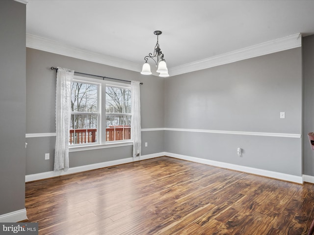 spare room with a notable chandelier, dark hardwood / wood-style flooring, and ornamental molding