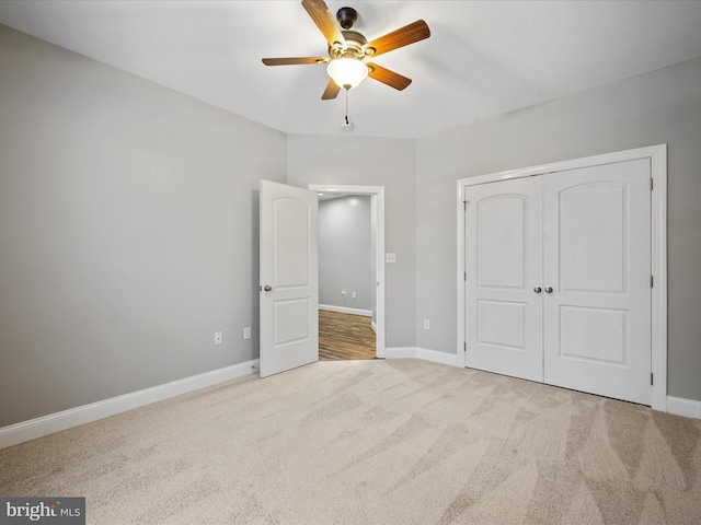 unfurnished bedroom featuring ceiling fan, a closet, and light carpet