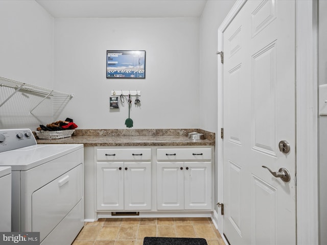 laundry area with light tile patterned flooring, washing machine and clothes dryer, and cabinets