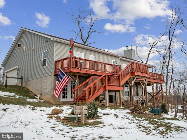 snow covered property with a wooden deck and a garage