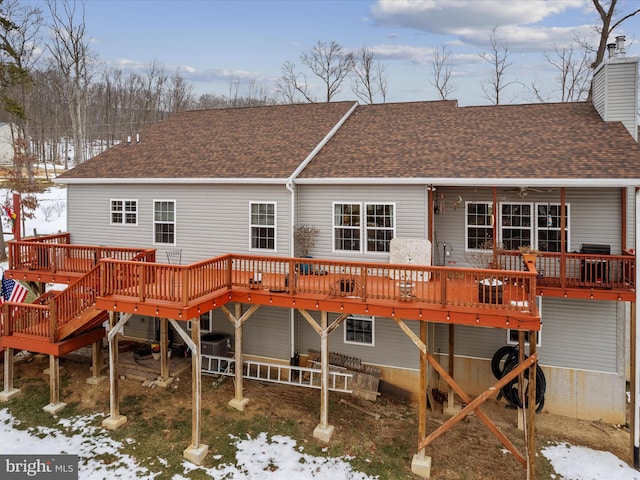 snow covered rear of property with central AC unit and a deck