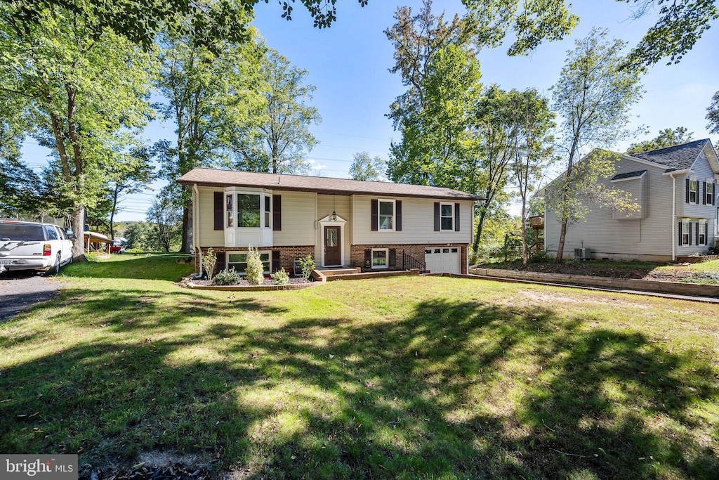 split foyer home featuring a front lawn and a garage