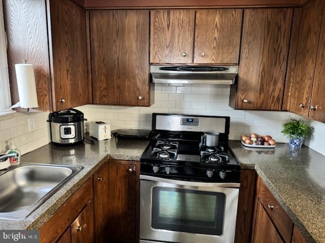 kitchen featuring decorative backsplash, stainless steel range with gas cooktop, and sink