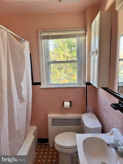 full bathroom featuring sink, tile walls, toilet, and shower / bath combination with curtain