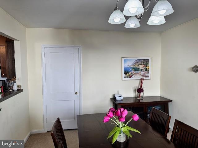 carpeted dining room with a chandelier