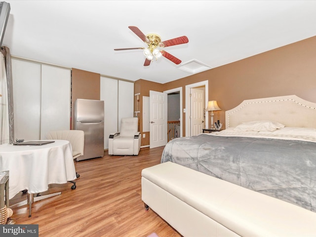 bedroom featuring multiple closets, ceiling fan, stainless steel fridge, and light hardwood / wood-style flooring