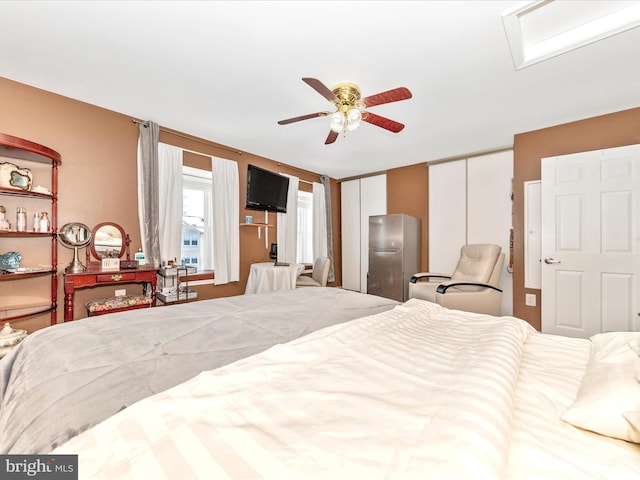 bedroom with multiple closets, stainless steel fridge, and ceiling fan