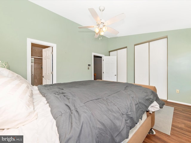 bedroom with hardwood / wood-style flooring, ceiling fan, lofted ceiling, and two closets