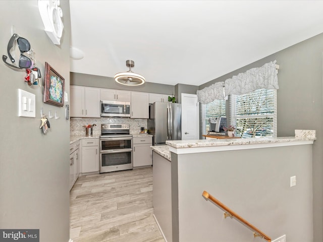 kitchen with white cabinetry, stainless steel appliances, light hardwood / wood-style floors, decorative backsplash, and kitchen peninsula