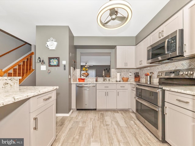 kitchen with stainless steel appliances, sink, white cabinets, and decorative backsplash