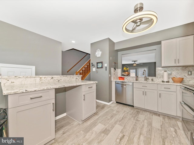 kitchen featuring tasteful backsplash, sink, stainless steel dishwasher, and light stone counters