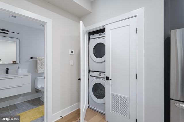 washroom with sink, tile patterned floors, and stacked washing maching and dryer