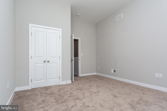 unfurnished bedroom with a closet and light colored carpet