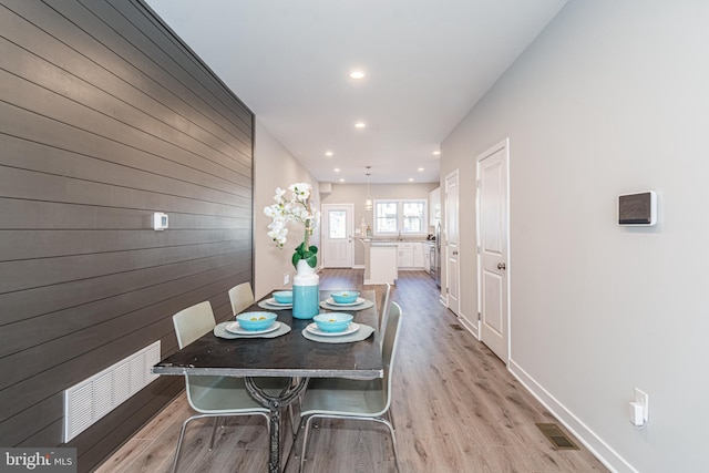 dining room with light hardwood / wood-style floors and wood walls