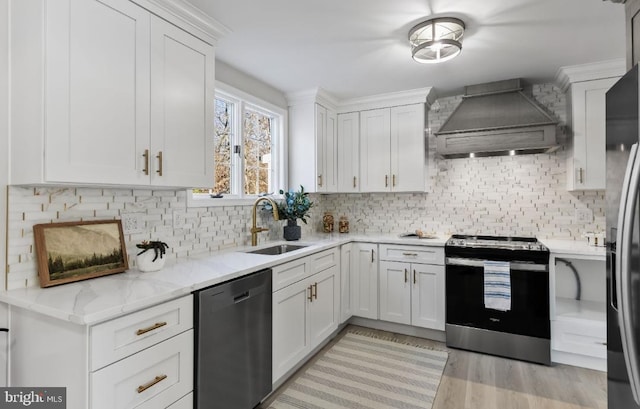 kitchen featuring sink, white cabinetry, light stone counters, premium range hood, and appliances with stainless steel finishes