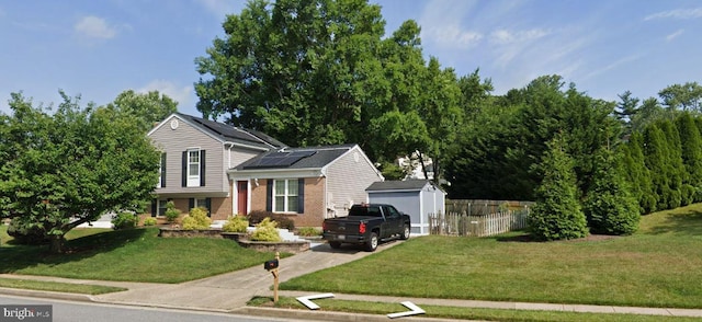 view of front of house featuring a front lawn, solar panels, and an outbuilding