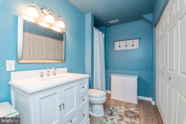 bathroom with hardwood / wood-style flooring, toilet, and vanity