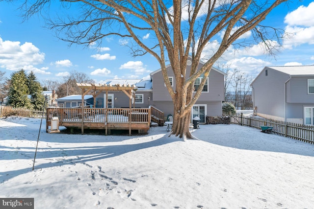 snow covered back of property featuring a pergola and a wooden deck