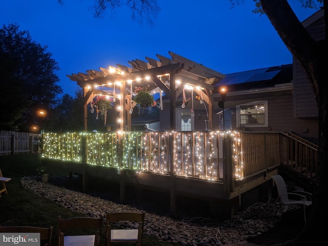 back house at twilight with solar panels and a pergola