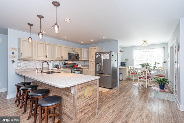 kitchen with cream cabinets, light hardwood / wood-style flooring, backsplash, appliances with stainless steel finishes, and sink