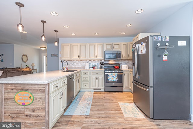 kitchen featuring appliances with stainless steel finishes, hanging light fixtures, decorative backsplash, sink, and cream cabinets