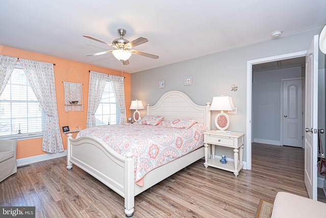 bedroom with ceiling fan, wood-type flooring, and multiple windows