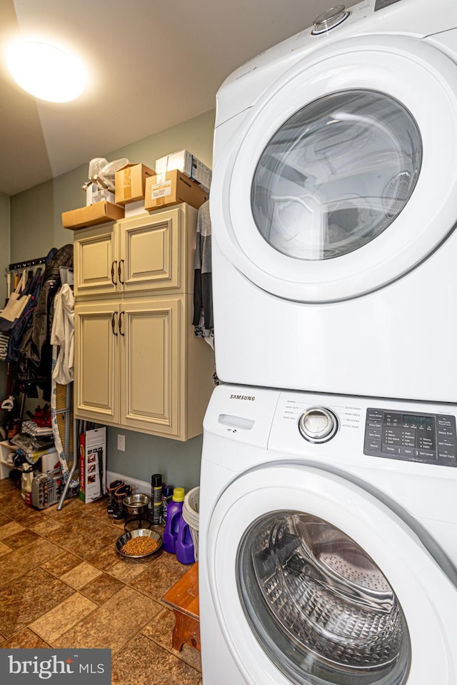 washroom featuring cabinets and stacked washer / dryer