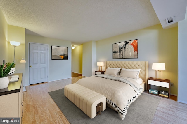 bedroom with light hardwood / wood-style flooring and a textured ceiling