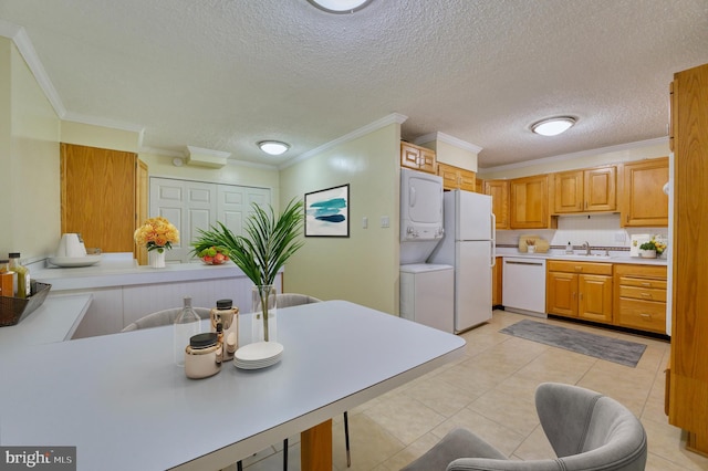 kitchen featuring sink, light tile patterned floors, ornamental molding, white appliances, and stacked washing maching and dryer