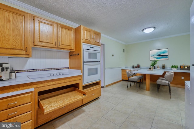 kitchen featuring light tile patterned floors, crown molding, white double oven, and a textured ceiling