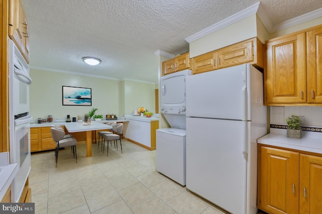 kitchen with crown molding, stacked washer / drying machine, and white appliances