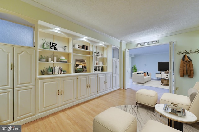 sitting room featuring ornamental molding, a textured ceiling, and light wood-type flooring