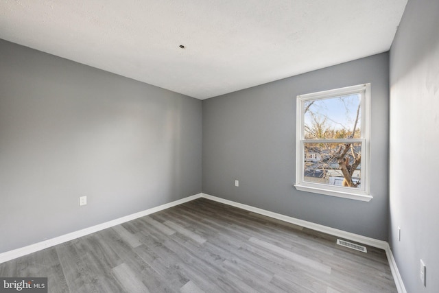 spare room featuring hardwood / wood-style floors and a textured ceiling