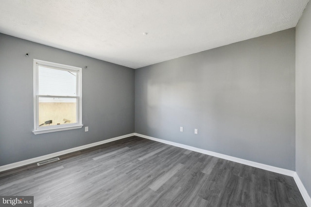 spare room featuring dark hardwood / wood-style floors and a textured ceiling