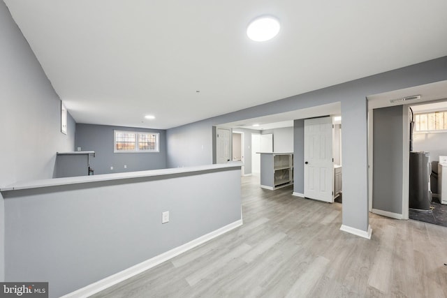 interior space featuring white cabinetry, independent washer and dryer, kitchen peninsula, and light wood-type flooring