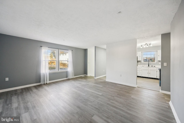 unfurnished room with a healthy amount of sunlight, a textured ceiling, and light hardwood / wood-style floors