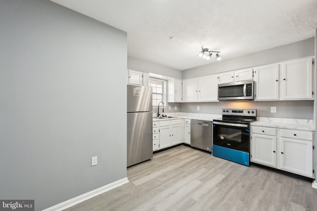 kitchen featuring sink, stainless steel appliances, white cabinets, and light wood-type flooring