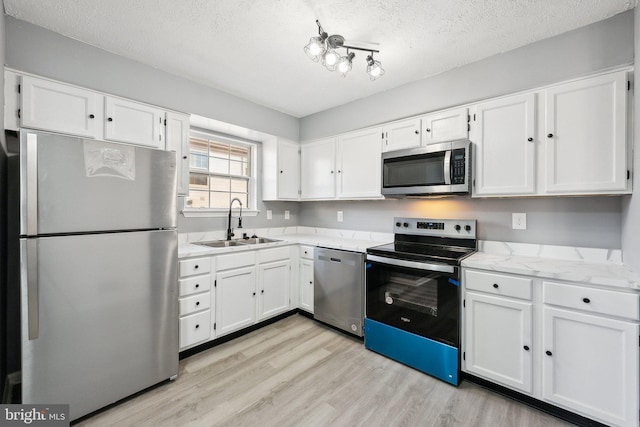 kitchen featuring appliances with stainless steel finishes, sink, white cabinets, and light hardwood / wood-style flooring