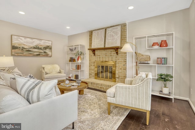 living area with dark wood-type flooring and a brick fireplace