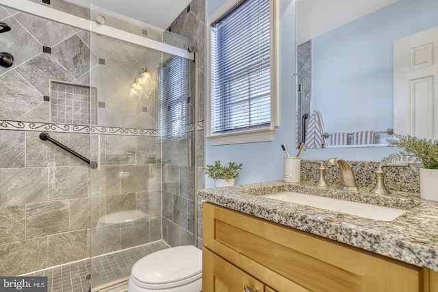 bathroom featuring vanity, a shower with shower door, and toilet